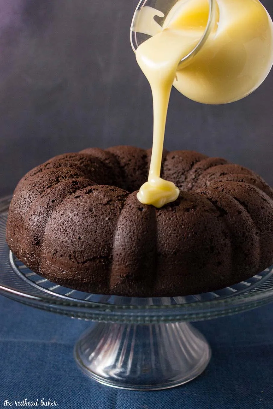 A shot of white chocolate icing being poured onto fudgy chocolate bundt cake. 