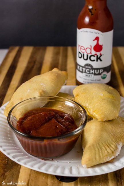 A plate of Philly cheesesteak empanadas with a bowl of Red Duck smoky ketchup for dipping.