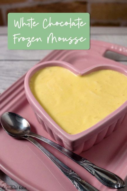 A ramekin of white chocolate frozen mousse on a pink serving tray.