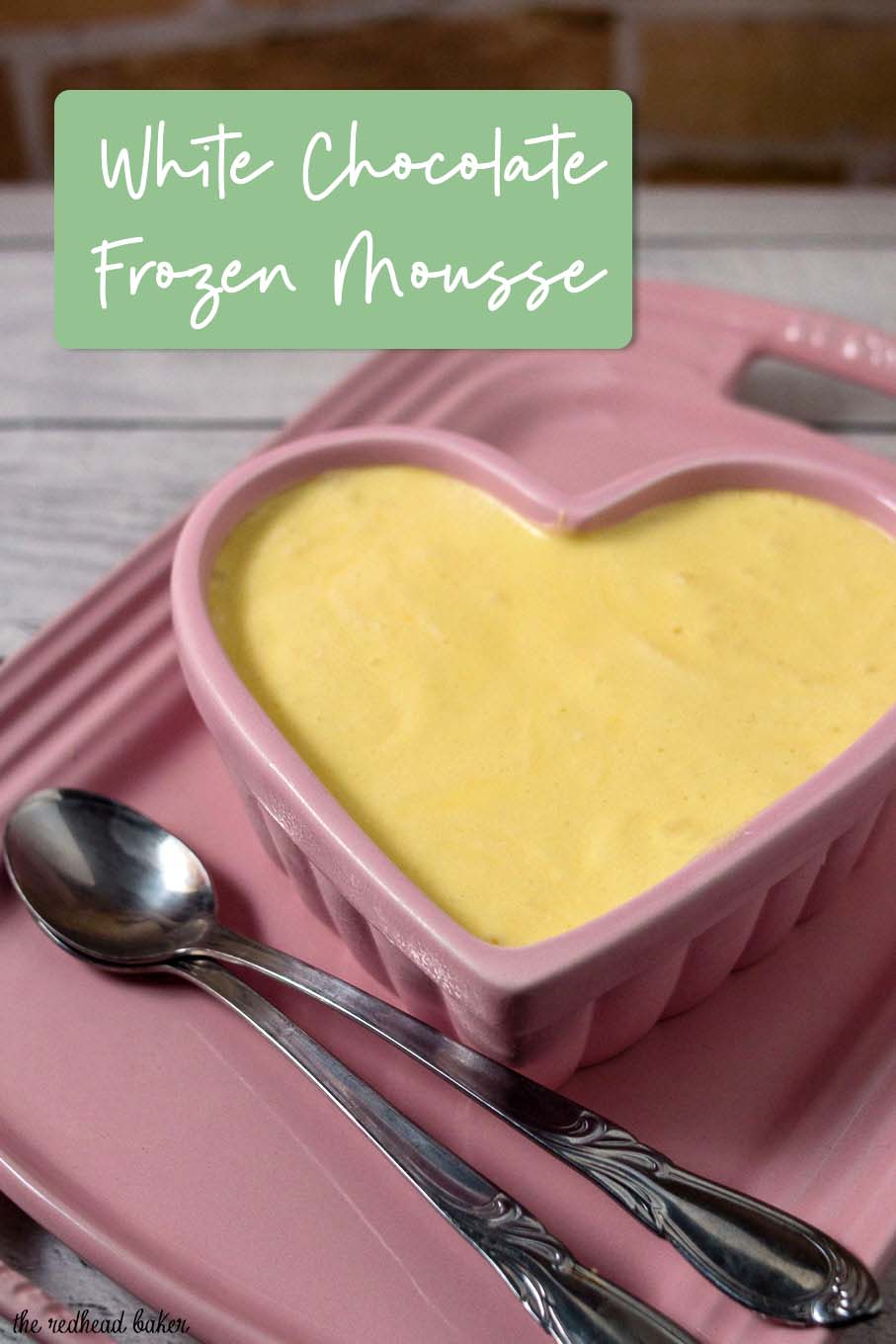 A ramekin of white chocolate frozen mousse on a pink serving tray. 