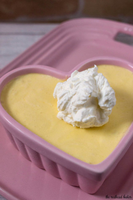 A ramekin of white chocolate frozen mousse with hazelnut whipped cream on a pink serving tray.