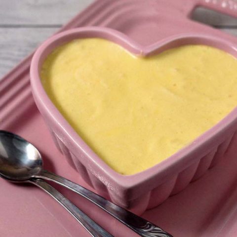 A ramekin of white chocolate frozen mousse on a pink serving tray.