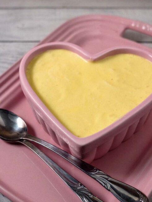 A ramekin of white chocolate frozen mousse on a pink serving tray.