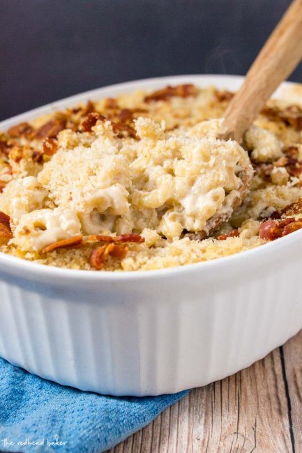 A wooden spoon digging into a casserole dish of Irish mac and cheese.