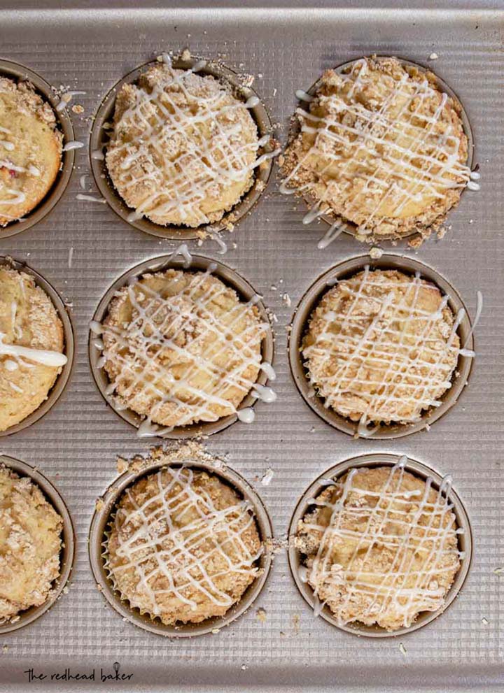 Six bakery-style peach crumb muffins in a baking pan.