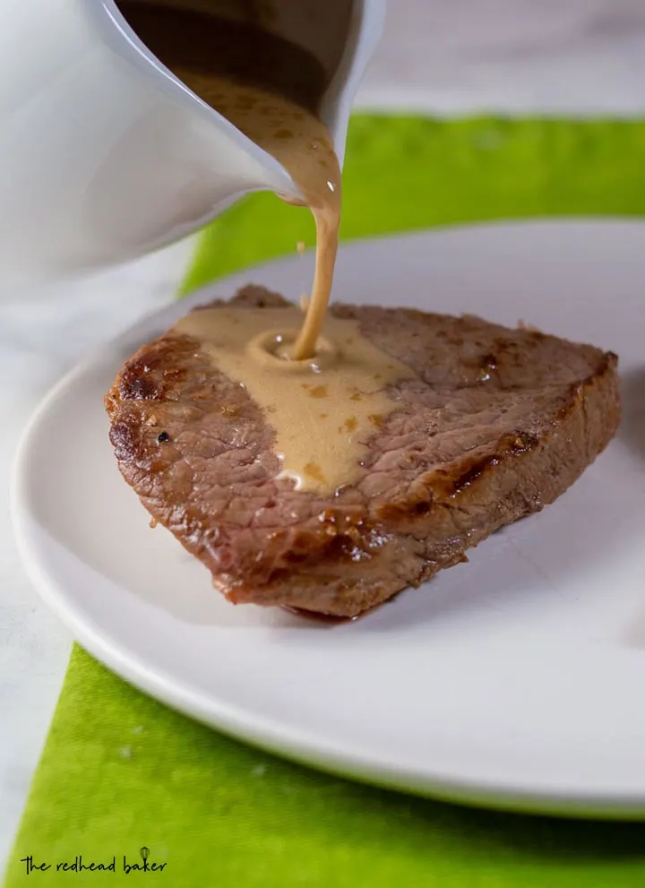 Whiskey sauce being poured onto a piece of steak