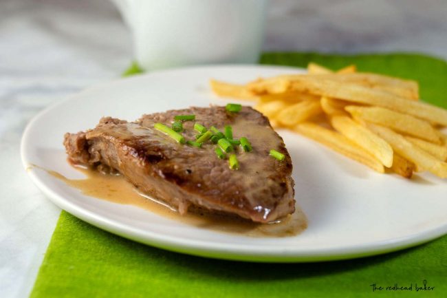 A plate of steak with whiskey sauce and a side of French fries