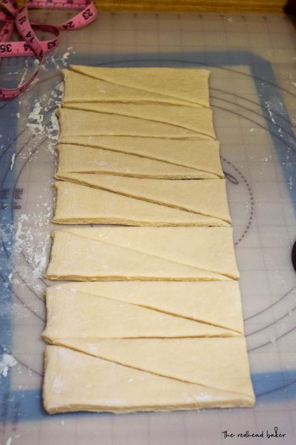 A strip of croissant dough cut into triangles.