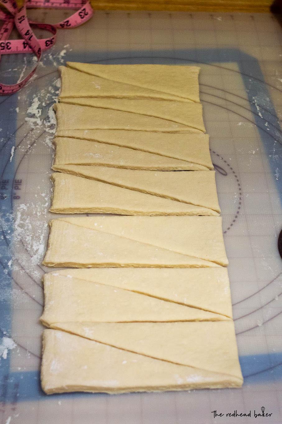 A strip of croissant dough cut into triangles.