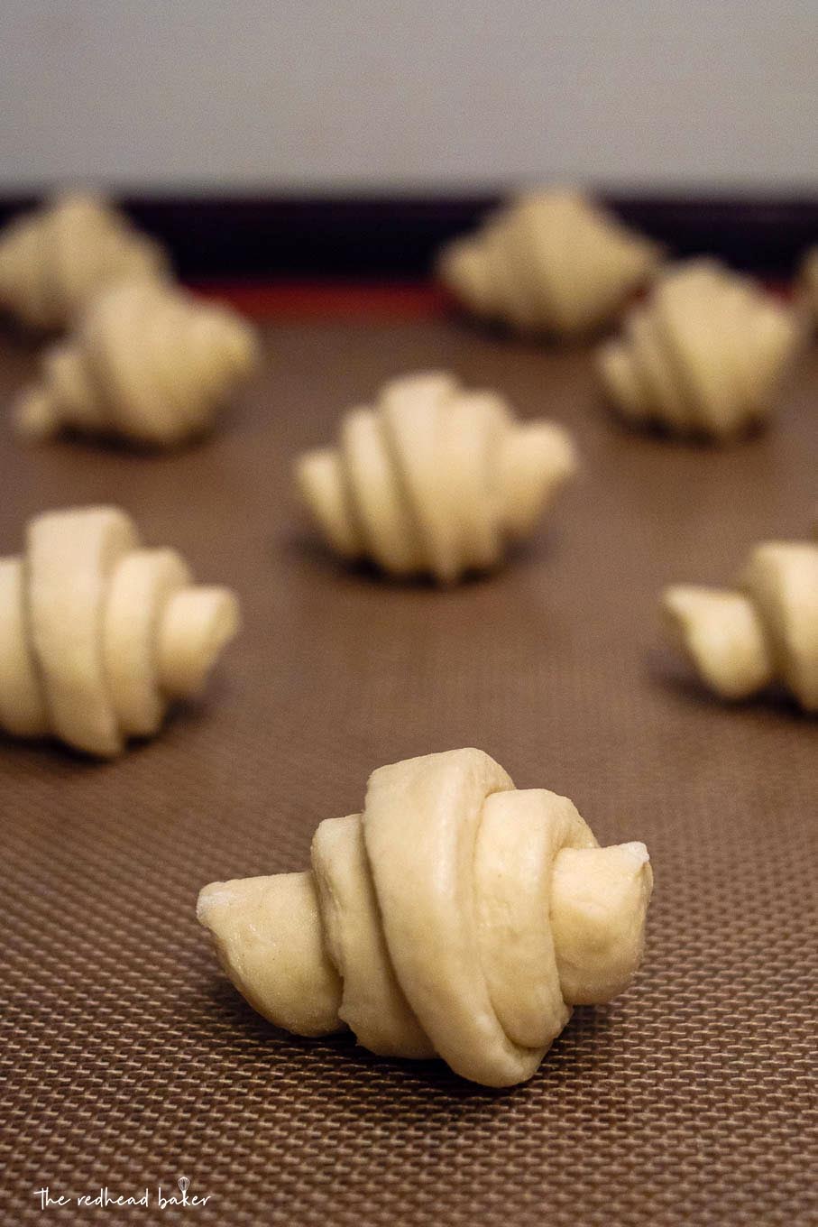 A baking sheet with 7 formed croissants ready to bake.