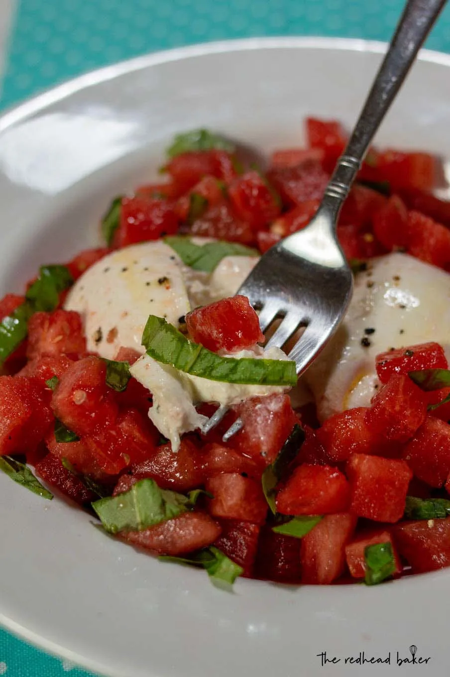 A dish of watermelon burrata salad with a fork