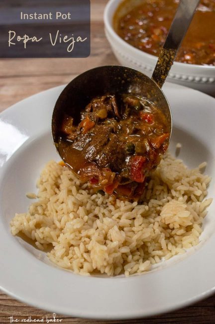 Ropa vieja being ladled on a serving of rice.