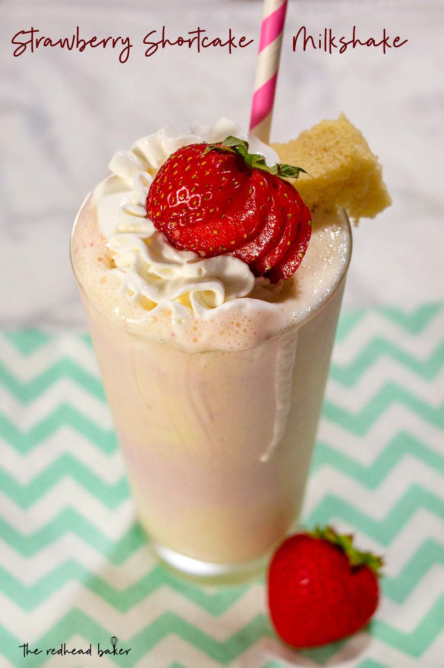 An overhead view of a strawberry shortcake milkshake garnished with whipped cream and a strawberry