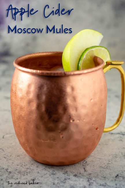 A close-up of a mug of Apple Cider Moscow Mule garnished with an apple wedge and a lime slice
