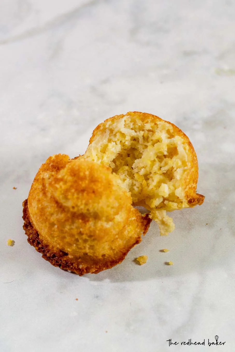 An apple cornbread cakelet broken in half to see the inner texture