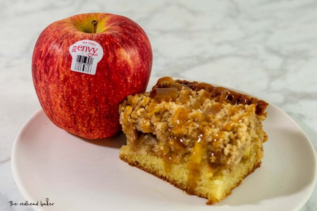 A slice of caramel apple crumb cake next to an Envy apple.