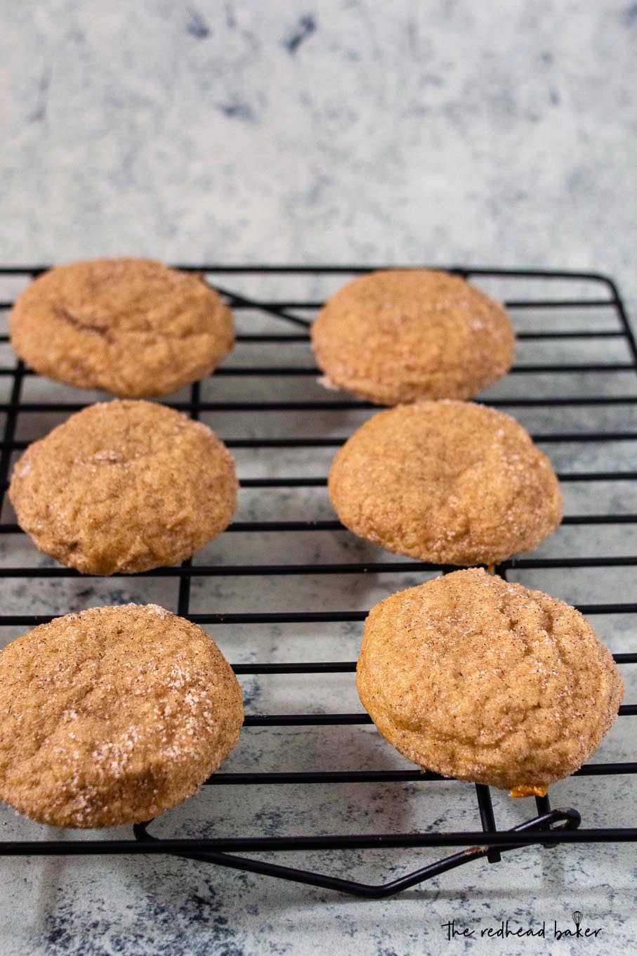 Baked caramel-stuffed apple butter snickerdoodles cooling on a wire rack