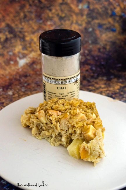 A triangle of chai-spiced baked apple oatmeal with a jar of The Spice House chai spice mix.