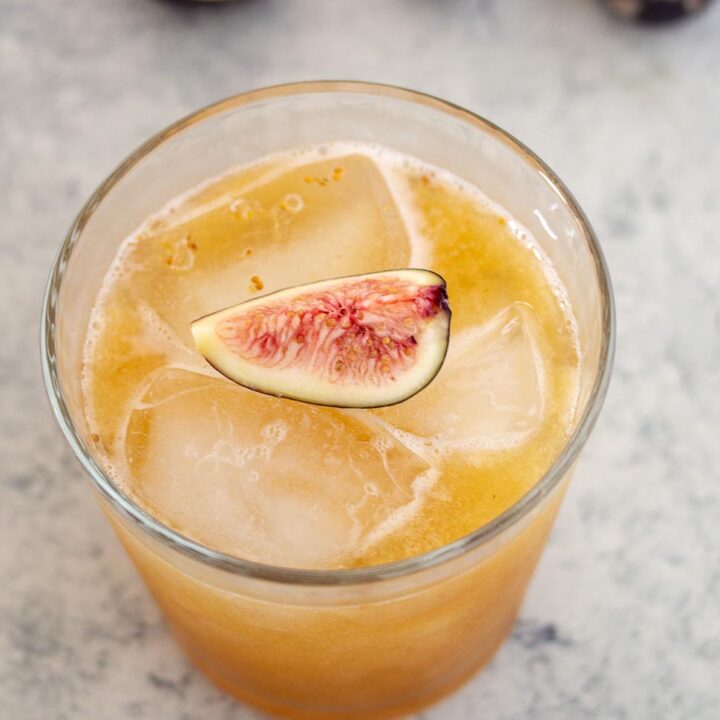 A high-angle shot of a honey-fig whiskey sour garnished with a fresh fig quarter