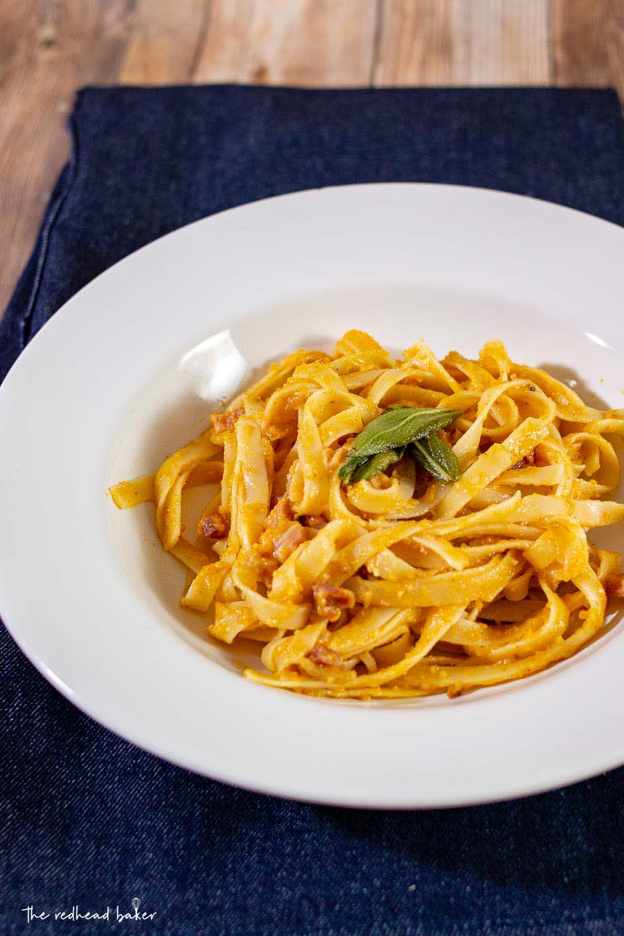 A dish of pumpkin carbonara with fried sage on a blue placemat.