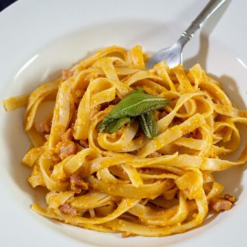 A serving of pumpkin carbonara in a white dish.