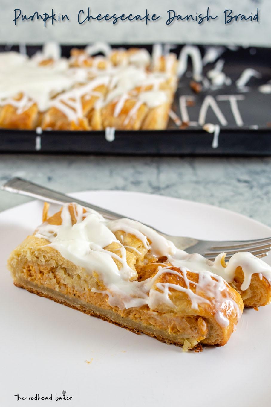 A slice of pumpkin cheesecake danish braid on a white plate in front of a black serving tray with the remaining braid.