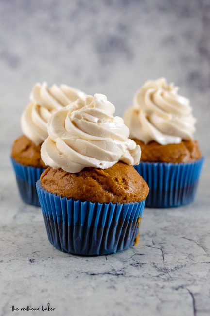 A straight-on view of three pumpkin cupcakes