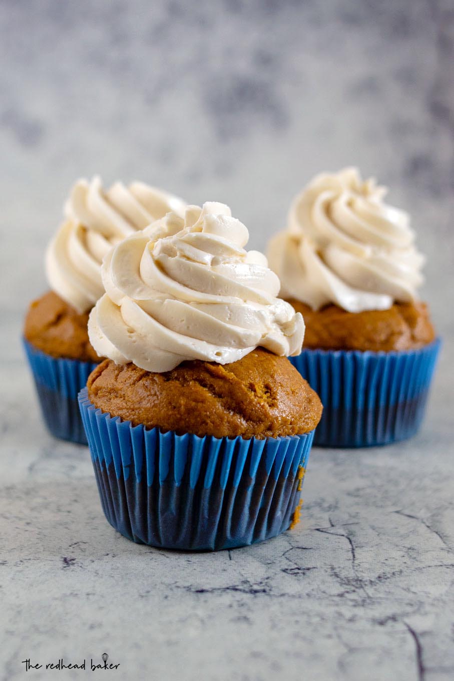 A straight-on view of three pumpkin cupcakes