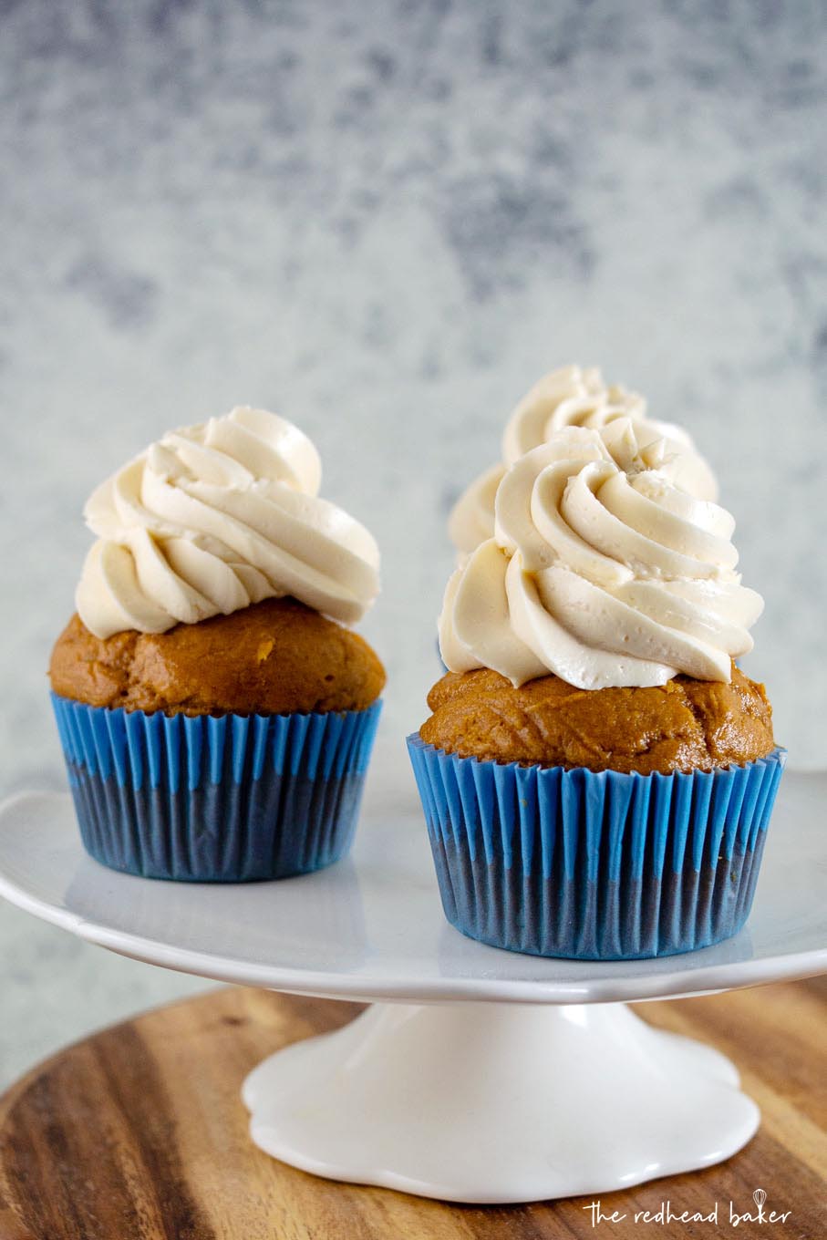 Two pumpkin cupcakes on a white cakestand