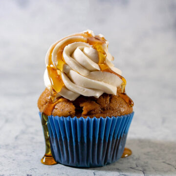 A close-up shot of a pumpkin cupcake with maple syrup dripping down the frosting