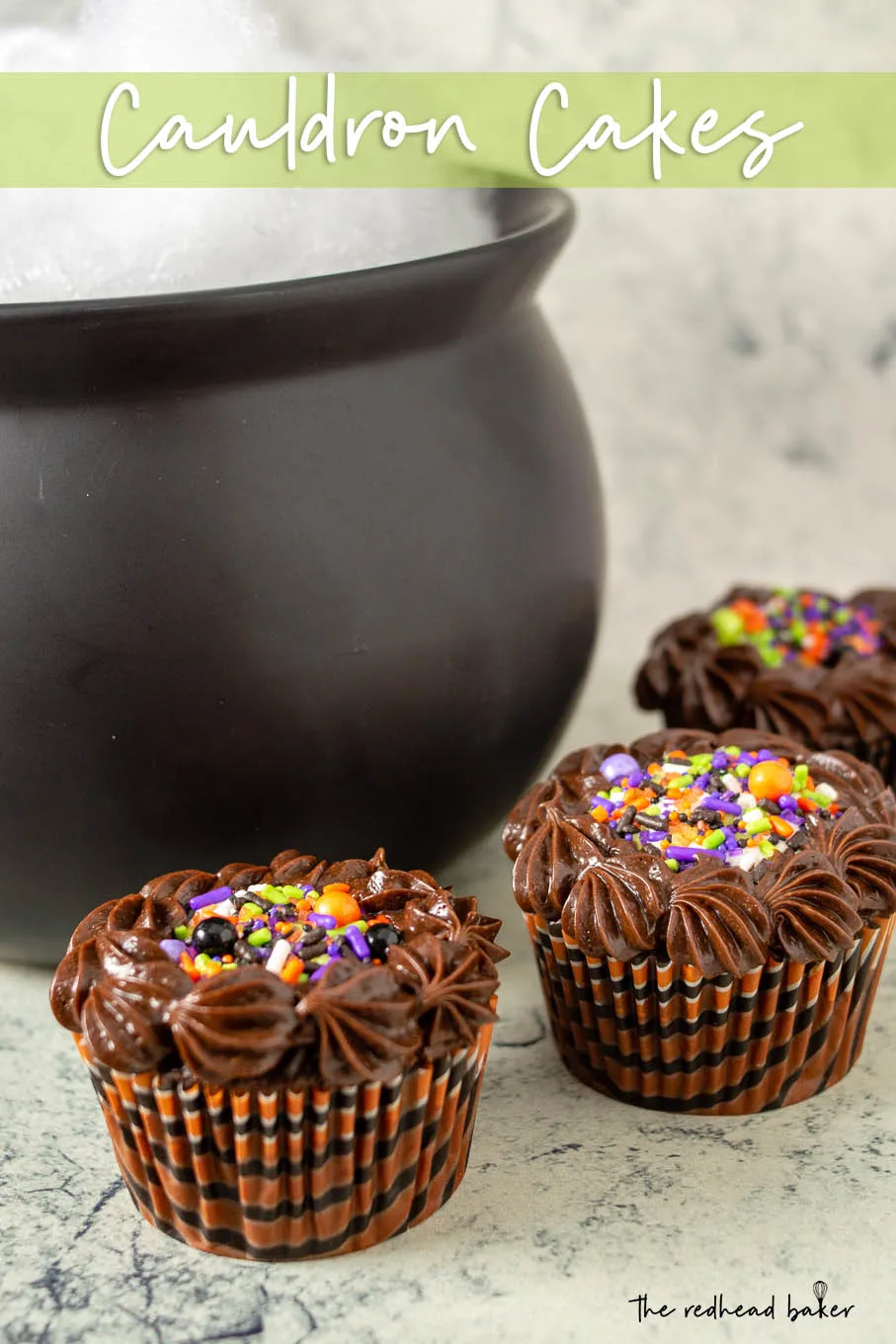 Three cauldron cakes in front of a cauldron