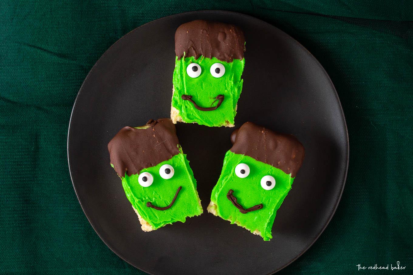 Overhead shot of three Frankenstein Crispy Cereal Treats on a black plate