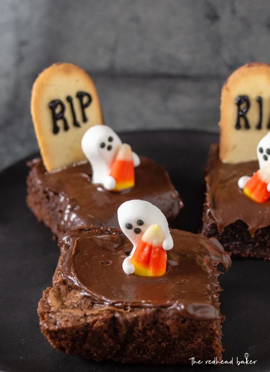 Three haunted graveyard brownies on a black plate