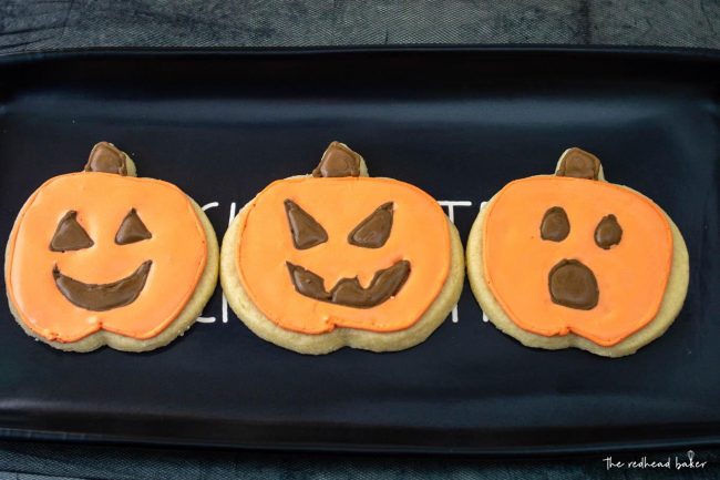 Three jack-o-lantern cookies on a black tray