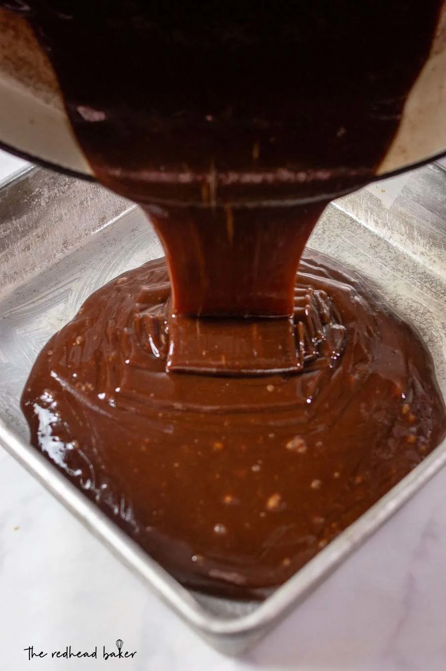 Old-fashioned chocolate fudge being poured into an 8x8 baking pan