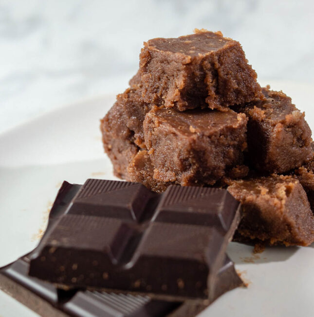 A pyramid of old-fashioned chocolate fudge next to unwrapped squares of Divine Chocolate 100% unsweetened baking chocolate