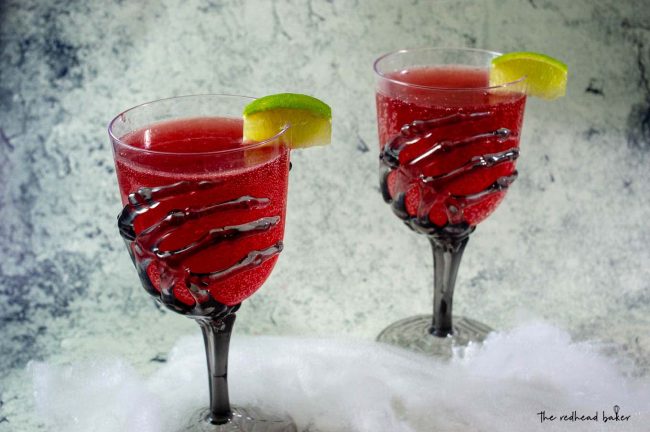 Two glasses of pomegranate margaritas in glasses with skeleton hand stems