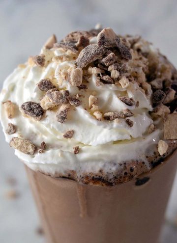 A triple chocolate malt milkshake garnished with whipped cream and crushed malted milk candies