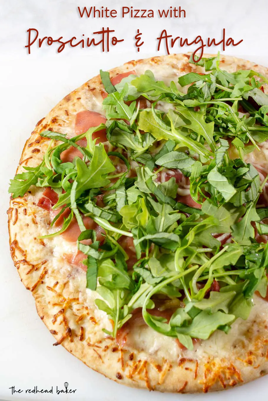An overhead photo of a whole white pizza with prosciutto and arugula