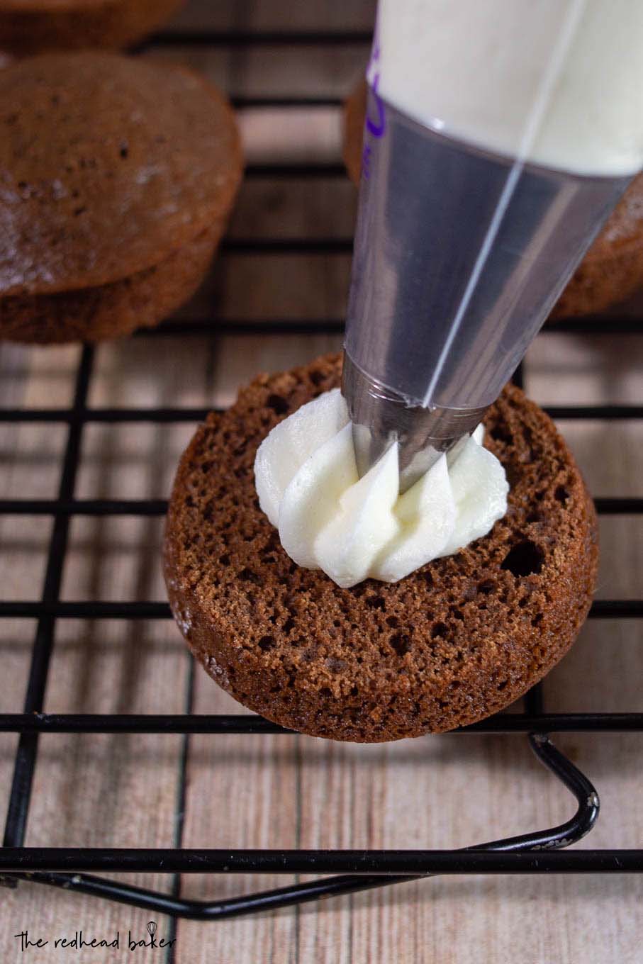 Peppermint filling being piped onto a chocolate whoopie pie