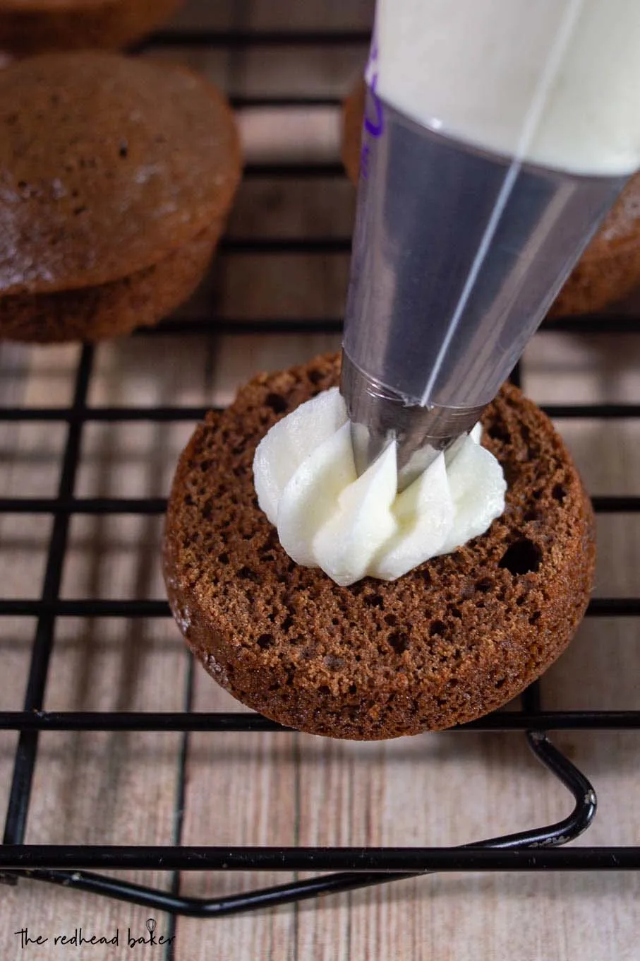 Peppermint filling being piped onto a chocolate whoopie pie