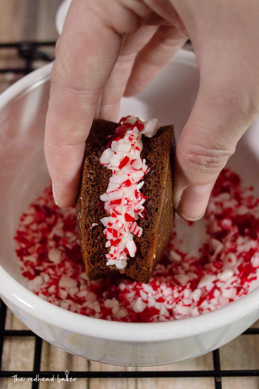 A chocolate peppermint whoopie pie being rolled in crushed peppermint candy