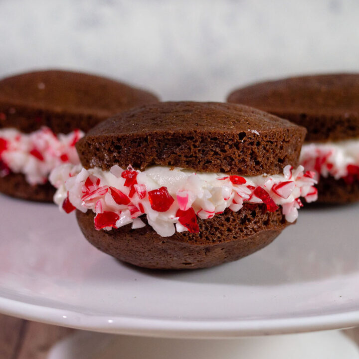 Three chocolate peppermint whoopie pies on a white cake plate