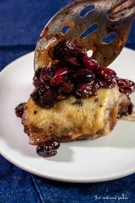 Cranberry balsamic sauce being spooned onto chicken thighs