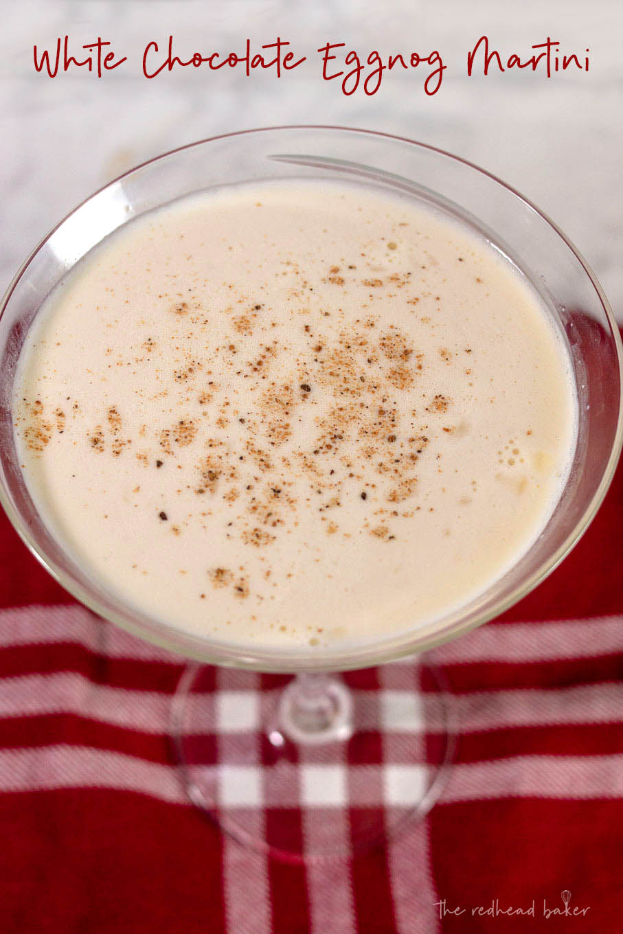 A white chocolate eggnog martini garnished with nutmeg on a red placemat.