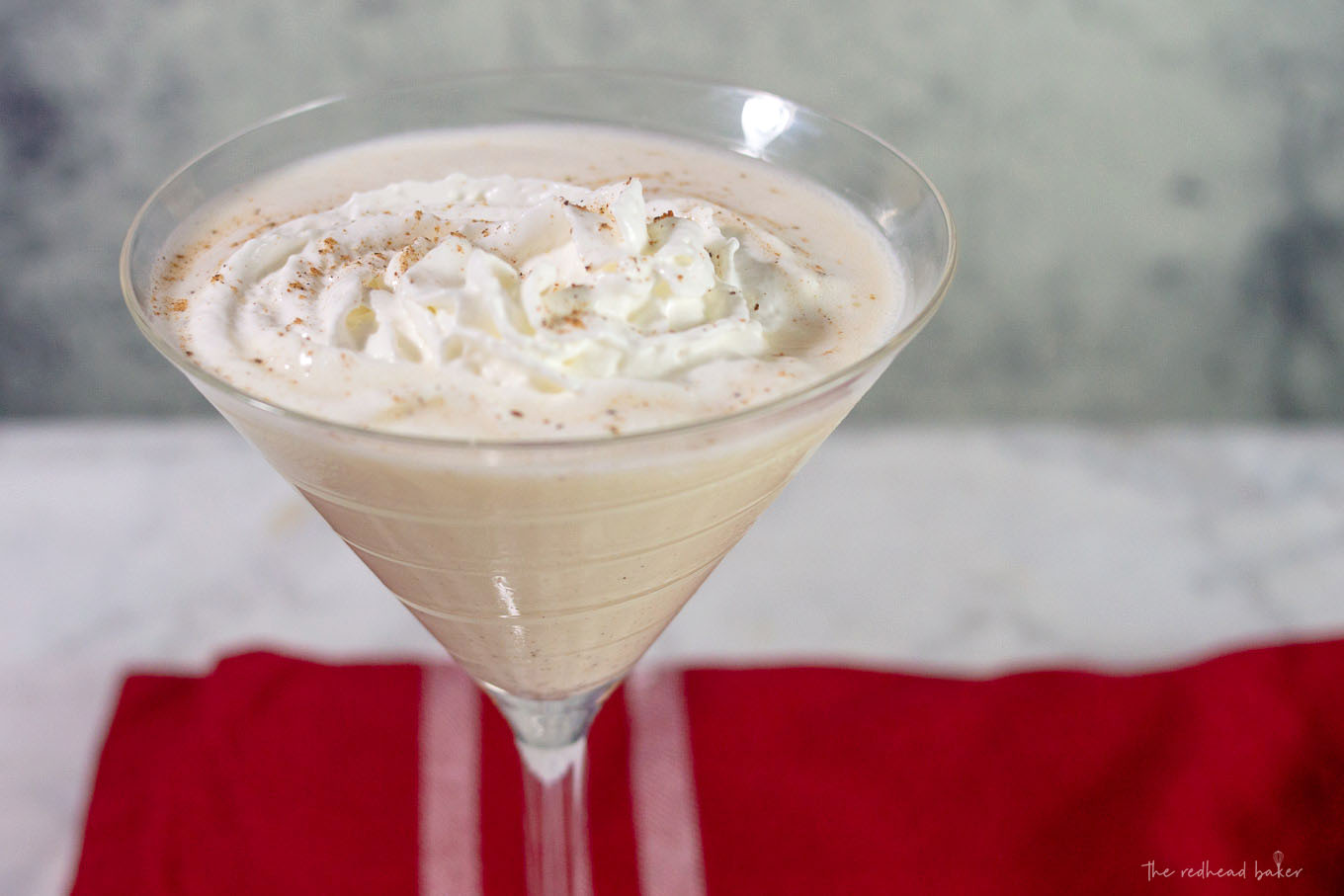 A white chocolate eggnog martini garnished with whipped cream and nutmeg