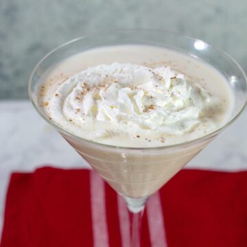 A white chocolate eggnog martini garnished with whipped cream