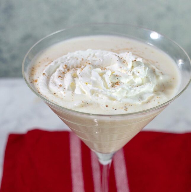 A white chocolate eggnog martini garnished with whipped cream