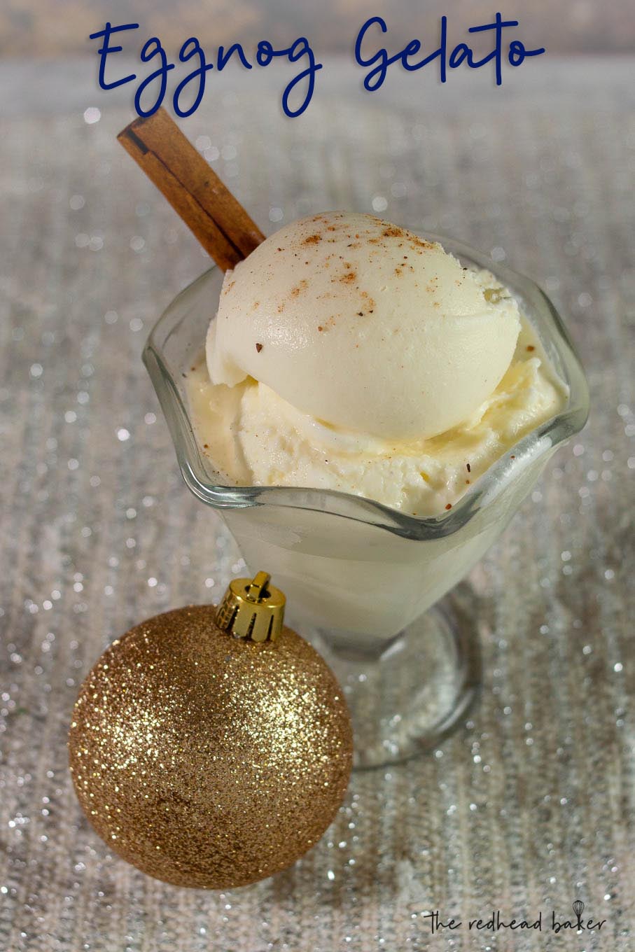 A dish of eggnog gelato with a cinnamon stick, and a glittery gold ornament in front of the dish