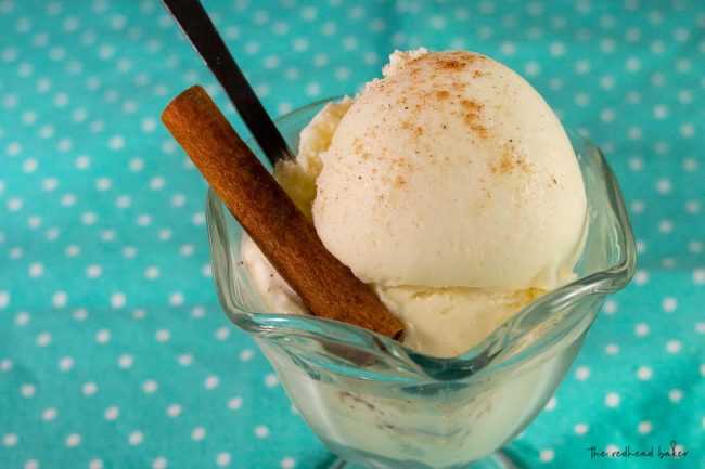 A dish of eggnog gelato with a cinnamon stick and a long ice cream spoon